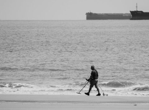 black and white photo of a man walking on a beach